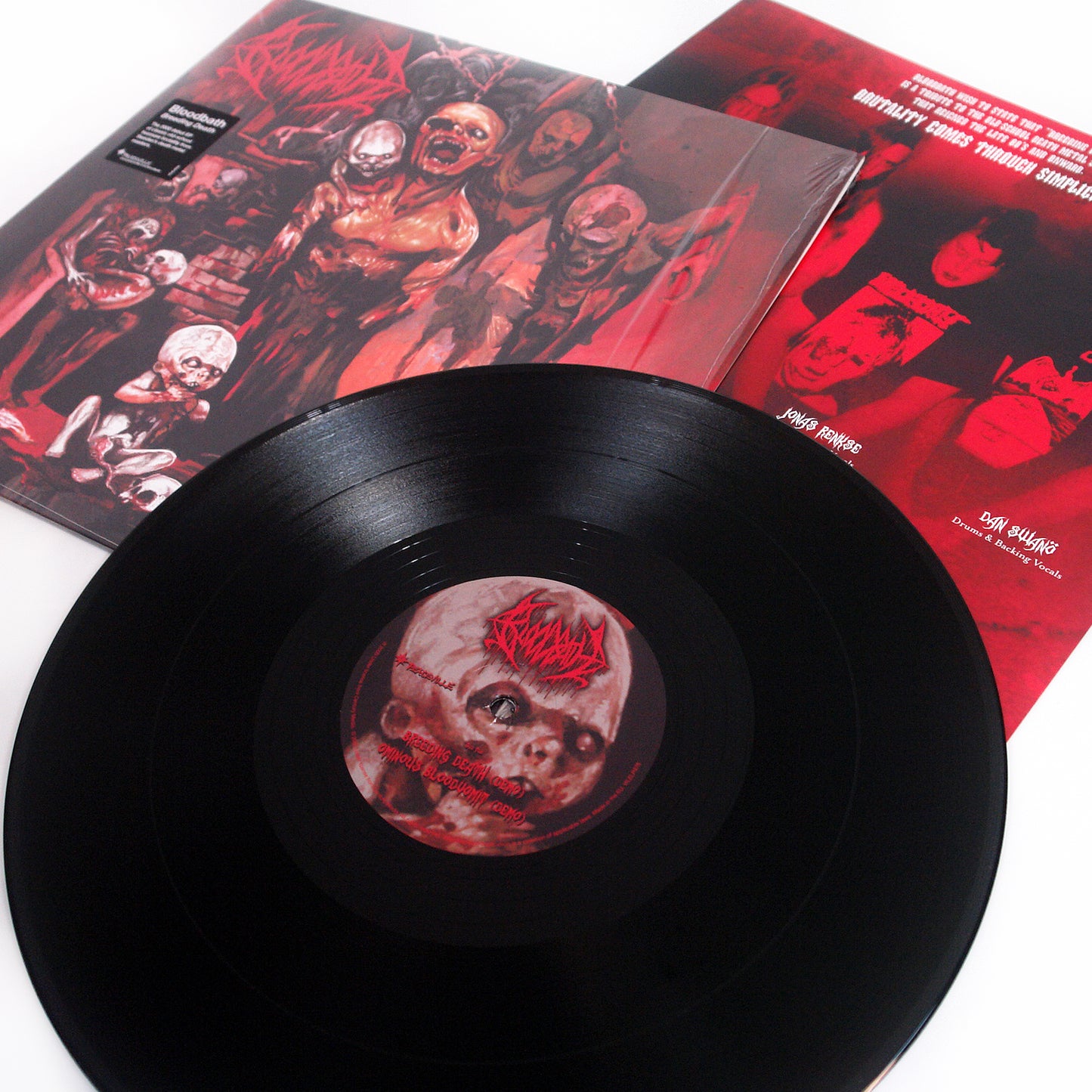 A Bloodbath black vinyl record with a label showing a sinister, bloodied doll face is displayed with its cover art and insert, both featuring gruesome horror-themed red and black illustrations.