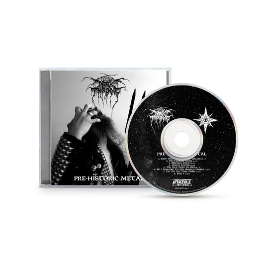 CD case and disc for "Pre-Historic Metal" by Darkthrone, featuring a black-and-white photo of a long-haired figure in metal-studded attire on the cover. The CD displays a starry night with the white Darkthrone logo, reflecting primitive metal roots.